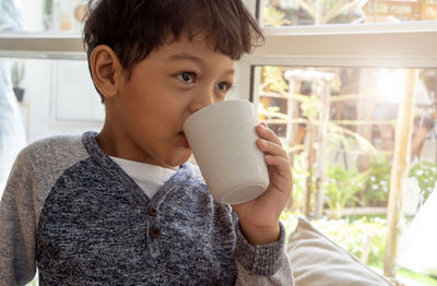 Close-up of boy drinking coffee sitting at home