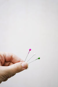 Cropped hand holding syringe against white background