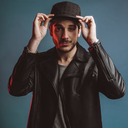 Portrait of young man wearing hat against blue background