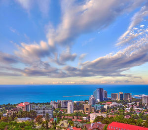 Cityscape by sea against sky