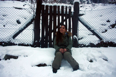 Full length portrait of woman sitting on snow