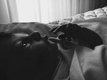 Close-up portrait of woman resting on bed at home