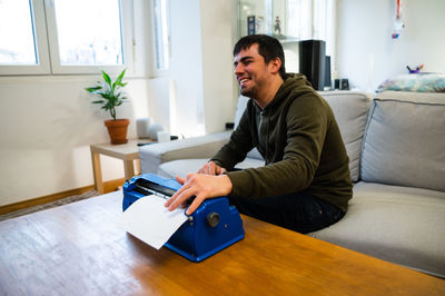 Young man using mobile phone while sitting on sofa