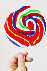 Close-up of hand holding ice cream over white background