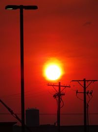 Low angle view of silhouette street light against orange sky