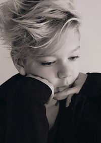 Close-up of boy with hand on chin against white background