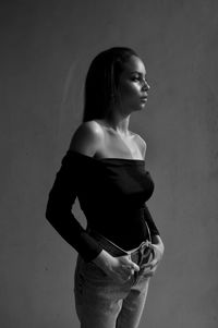 Woman looking away while standing against wall