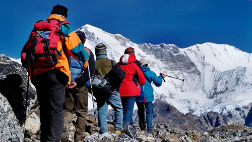 Rear view of people hiking at snowcapped mountain