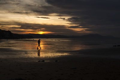 Silhouette of man on beach at sunset
