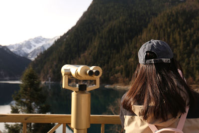 Rear view of woman photographing through binoculars