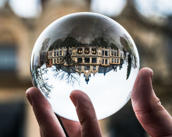 Close-up of hand holding crystal ball with reflection