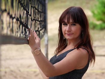 Smiling young woman standing by net