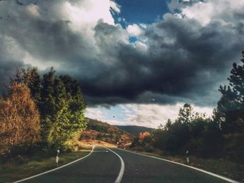 Road by trees against sky