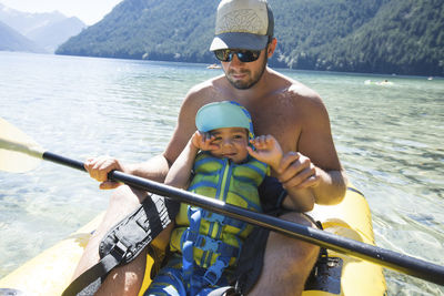 Father helping son paddle an inflatable kayak.