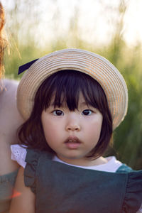 Koreans family mother and daughter in green dresses sitting in the long grass on the field at sunset