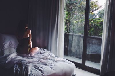 Woman sitting on bed at home