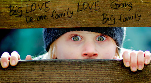 Close-up portrait of girl peeking by fence