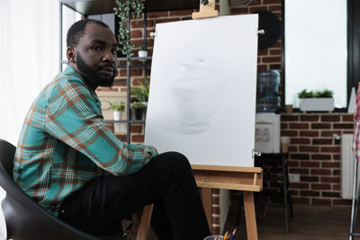 Side view of man using laptop while sitting on table