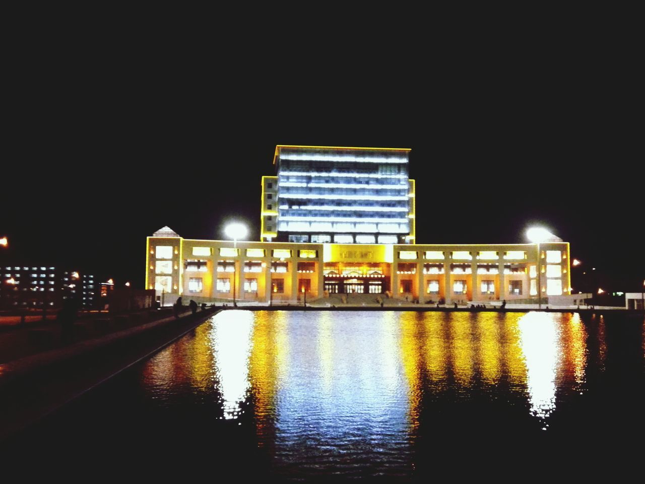 illuminated, night, architecture, building exterior, built structure, reflection, water, city, waterfront, clear sky, building, river, copy space, city life, sky, modern, outdoors, no people, street light, travel destinations