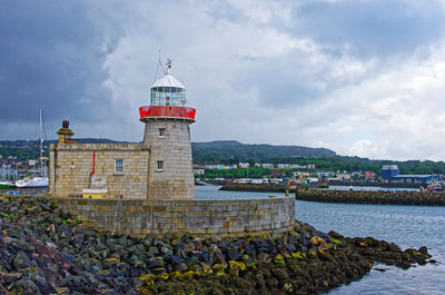Lighthouse by sea against sky