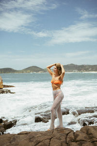 Full length of woman standing at beach against sky