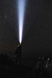 Low angle view of person against illuminated star field at night