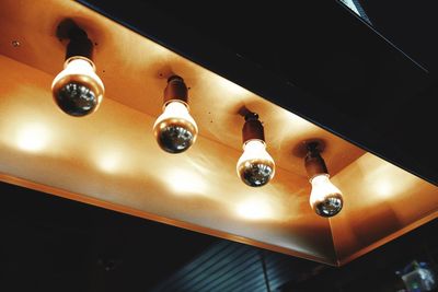 Low angle view of illuminated pendant lights hanging from ceiling