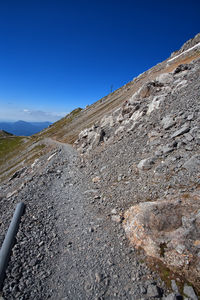 Low angle view of rocky mountains against clear blue sky