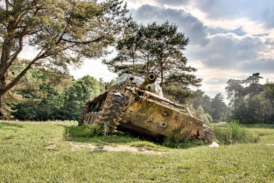 Old abandoned car on field against sky