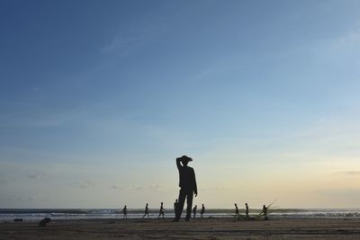 Silhouette man on beach against sky during sunset