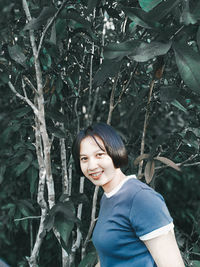 Portrait of smiling young woman standing in forest