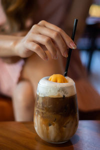 Close-up of hand holding drink on table