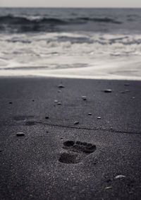 Footprints on sand at beach against sky