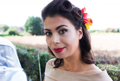 Close-up of smiling woman by vintage car against sky