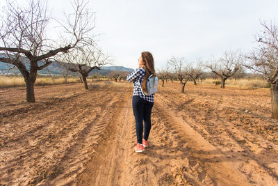 Full length of woman on bare trees against sky