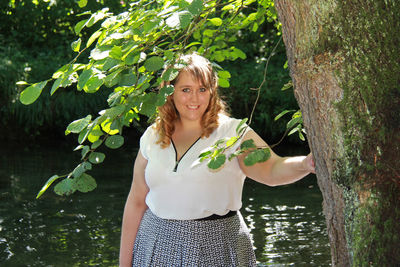 Portrait of young woman standing against plants