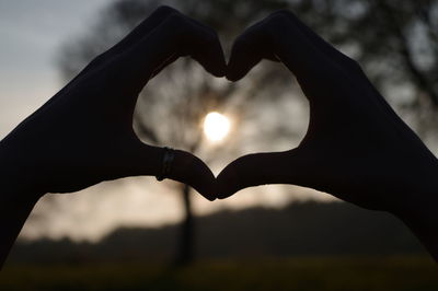 Close-up of silhouette hands making heart shape during sunset