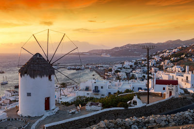 Buildings by sea against sky during sunset