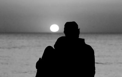 Silhouette man at beach against sky during sunset