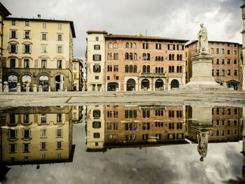 Buildings in city against cloudy sky