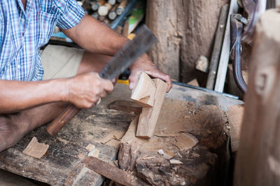 Midsection of man cutting wood in workshop