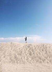 Full length of man on sand at beach against blue sky