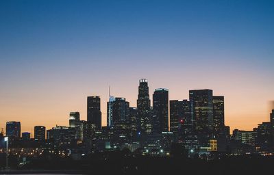 Illuminated buildings against sky during sunset