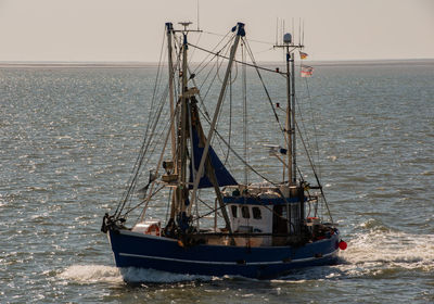 Fishing boat sailing on sea against clear sky