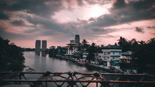 River by buildings against sky at sunset