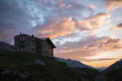 Low angle view of house and mountains against sky during sunset