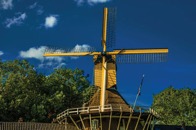 Wooden yellow windmill next to tree-lined canal at weesp. a pleasant small village in netherlands.