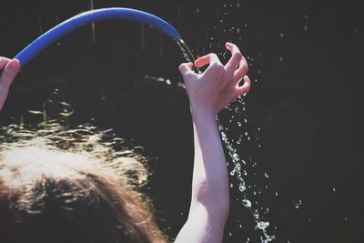 Cropped image of child playing with water hose