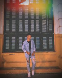 Portrait of young man standing against window