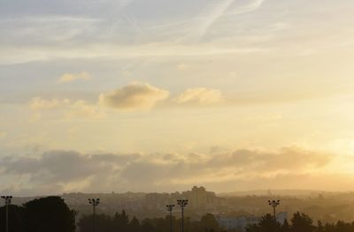 Silhouette trees and buildings against sky during sunset